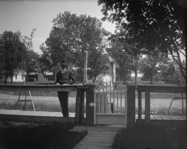 Man and woman standing outside a gate for a yard fenced-in with chicken wire.