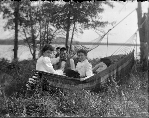 Men and women sitting in two hammocks. The people pictured are Julia Murray Ormsby, Fred Werner, and R. Effie (Ettie) Meinhold.