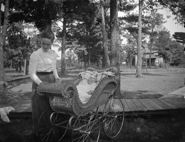 Woman, probably Mrs. Rufus A. Jones, the former Birdine Perry, posing with an infant in a baby carriage.