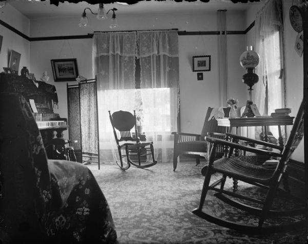 Interior of a parlor showing a piano and rocking chairs.