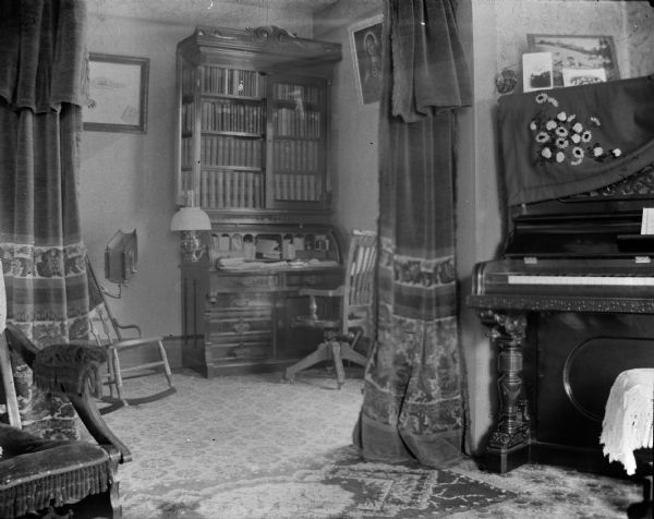 Interior of room with a piano and bookcase desk.