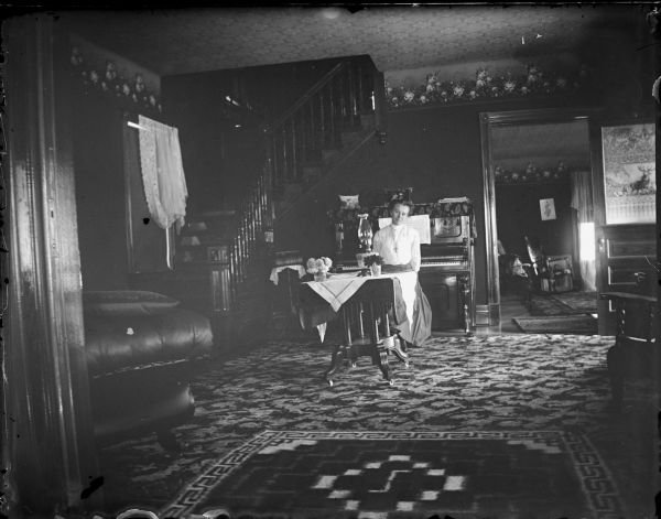 Woman sitting at a piano in a parlor.