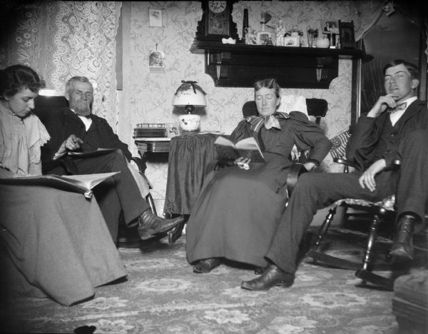 Two men and two women reading in a parlor, possibly J.R. Ogden and wife, and Grace Ogden and Carl (?).