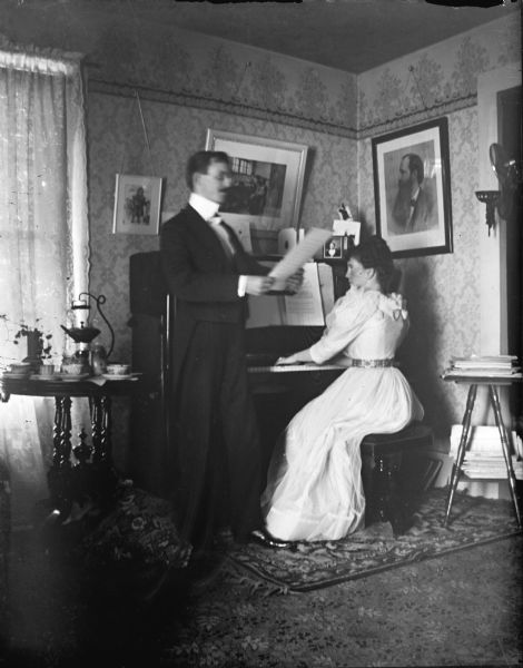 Man singing as a woman plays a piano.