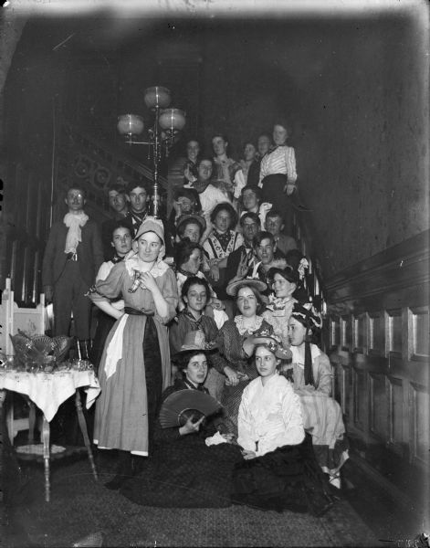 Large group posed on a staircase, possibly a fancy dress party.