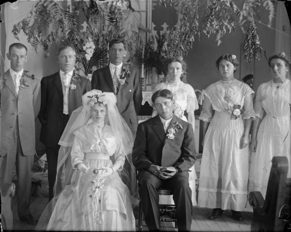 Seated bride and groom with standing attendants.