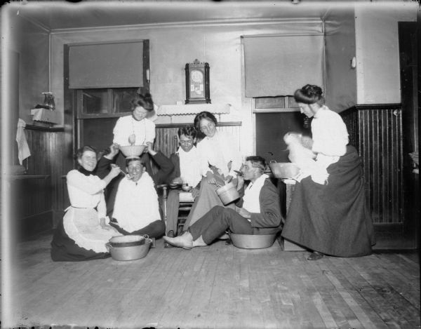 Three men and four women with pots and pans in a kitchen.