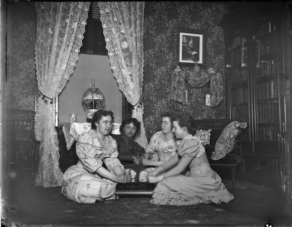 Four women sitting on the floor playing a game. Includes the Spaulding twins.
