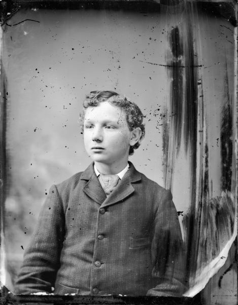 Studio portrait of a young boy with curly hair.
