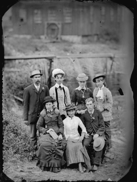 Group portrait of a man and three women standing behind two seated women and a man in an outdoor setting.