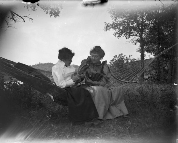 Two women sitting in a hammock.