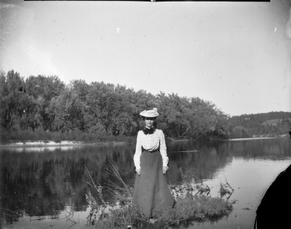 Woman posed standing on a small island or peninsula in the river.