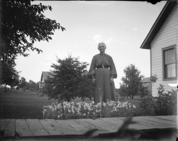 Woman posed standing by a flower patch.