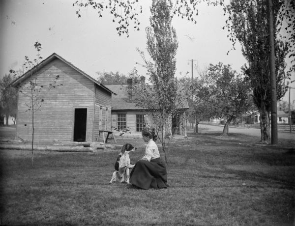 Woman posed kneeling in a yard shaking hands with a dog.