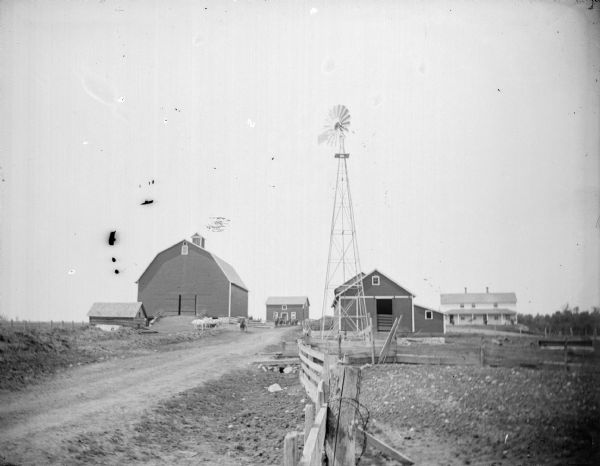 Farm buildings, including a farmhouse and a windmill.