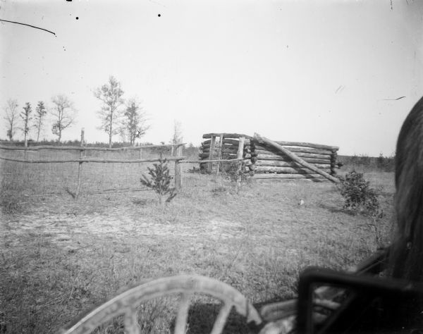 The structure of a log cabin as seen from a horse-drawn vehicle.