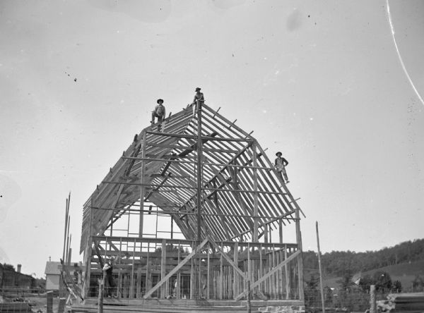 Four men work on the framework of a barn.