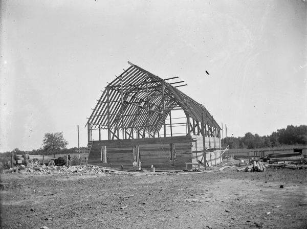 The wooden framework of an unfinished barn with the lower boards attached.