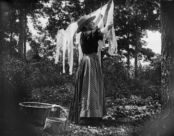 A woman hangs laundry on a clothesline.