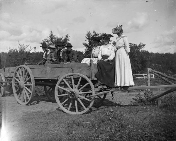 Four men and three women pose on a wagon.