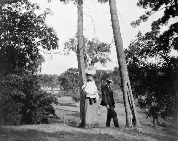 A well-dressed man, woman and child walk through a wooded area.