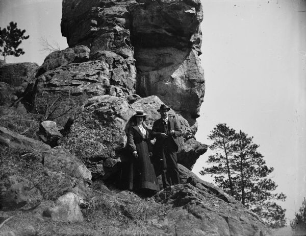 A man and woman stand on a large rock outcropping, possibly Chimney Rock near Alma Center.	