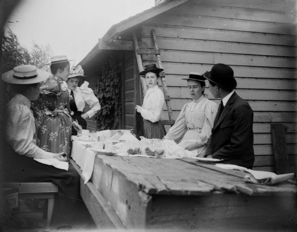 One man and four women gather around a picnic table.