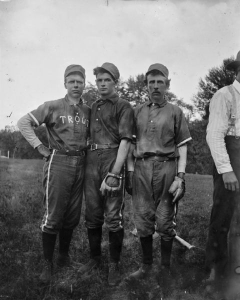 Three baseball teammates pose outdoors.