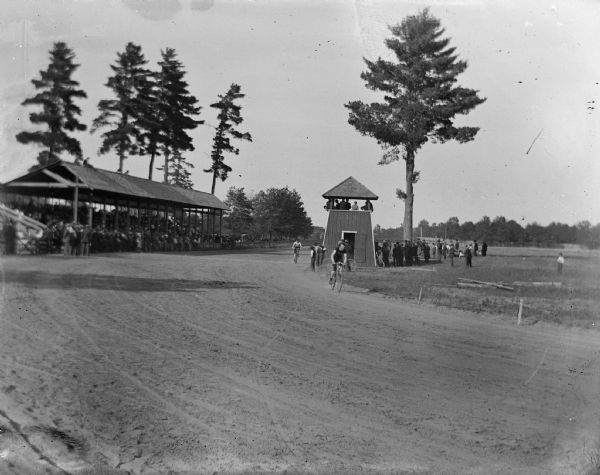 Cyclists turn a corner at the Jackson County Fairground racetrack. In the background, the judges' stand and grandstand are visible.