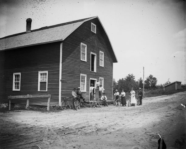 A group of men and women pose with bicycles outside of the Charter Oak Mill on Highway 54, south of Black River Falls.