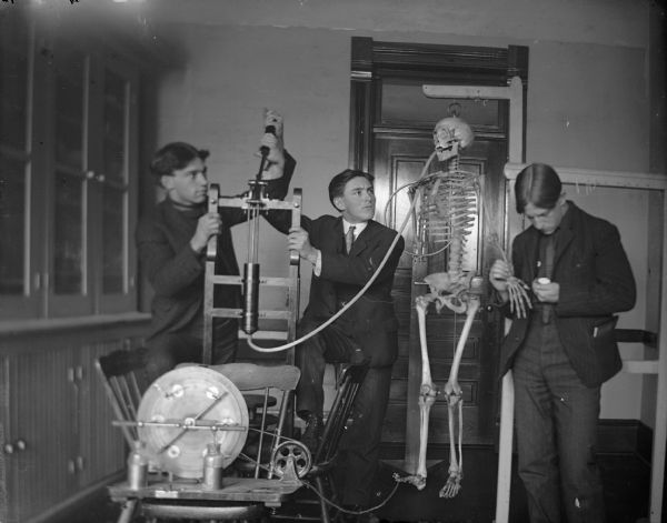 Three medical students, right to left: Roy Van Schaick, Price Arnold, and Clyde Harmer play with medical equipment and a skeleton. Reportedly, the name of the skeleton was Susan Allbones, whom Roy brought home from Milwaukee.