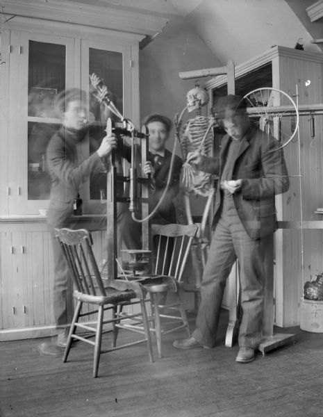 Three men horse-play with a skeleton and medical equipment. From right to left, Roy Van Schaick, Price Arnold, and Clyde Harmer. Reportedly, the name of the skeleton was Susan Allbones, whom Roy brought home from Milwaukee