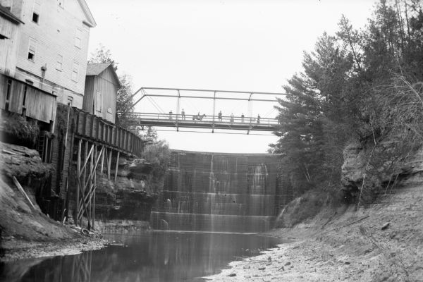 People stand on the bridge over a dam, probably the Douglas Dam and Mill near Melrose.	