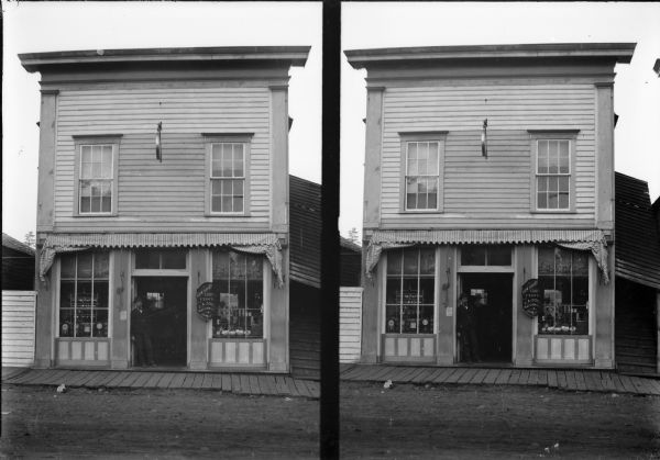 A man stands in the entryway of J.A. Eckern's jewelry store. A dual view, possibly a stereograph.