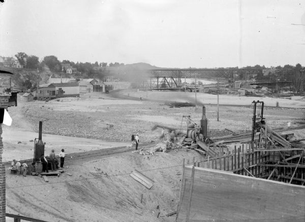 Elevated view of Black River Falls after the flood of 1911. Several men and youth are visible in the foreground, in addition to the new dam construction.