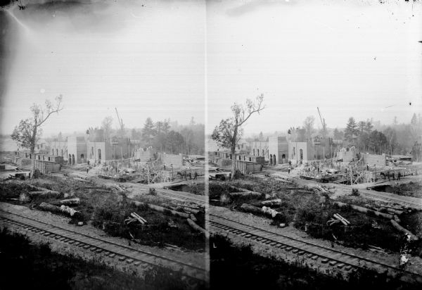 A possible stereograph of numerous men constructing an unidentified building next to railroad tracks.