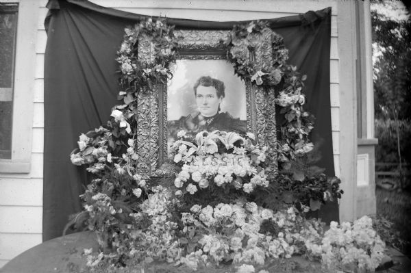 Painted portrait of a woman with the name "Lessie" among funeral wreaths.