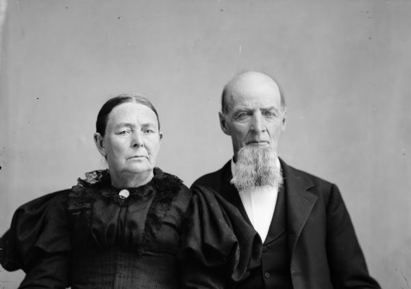 A studio portrait of an elderly couple, probably Lawrence Washington Burge and Emmeline Elizabeth Barney Burge. The man is wearing a suit jacket, and the woman has a dress with a lace collar and puffed sleeves.