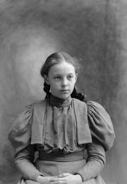 A studio portrait of a seated girl with freckles.