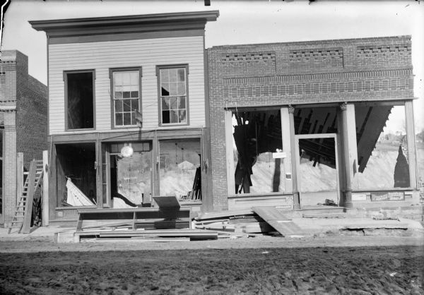 View from street of remaining storefronts of two damaged buildings.