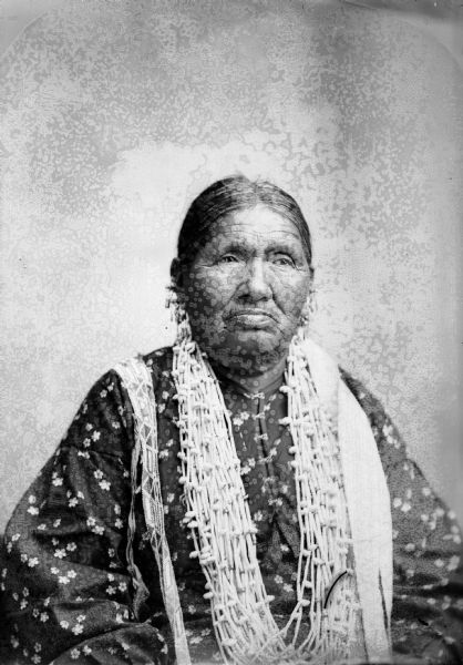 Studio portrait of a Ho-Chunk woman posing sitting and wearing several necklaces. Betsy Thunder, who was reportedly a medicine woman.