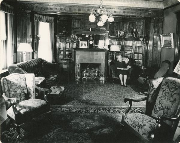 The living room of Fred and Annie Storer Brown's home (built 1888), 121 East Gilman Street.  Annie Hepworth Storer Brown sits by the fireplace.