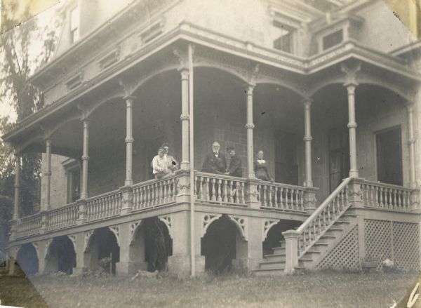 View of the side porch of the Storer residence, 104 East Gilman Street. (aka Kendall House) Harvey Conorer, about six years old, sits on the far left, with Annie Brown(?) standing behind him.  George Storer stands to their right, followed by Timothy Brown, about 8 years old, and Mary Storer on the far right.