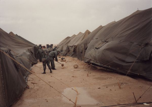 Soldiers securing tents for a wind and sand storm in Saudi Arabia during the Persian Gulf War.