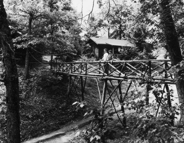 Couple on a wooden bridge over a dirt road at Birchcliff Lodge.