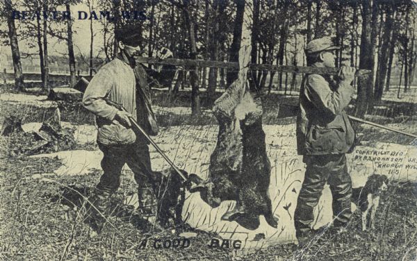 Two hunters, rifles in hand, transport the giant rabbits they have killed homeward.  They have tied the rabbits to a wooden pole, which they rested between them on their respective shoulders.  Through the snowy forest, in the distant background, a fence and some houses can faintly be seen.  A hunting dog stands at one of the hunter's sides.