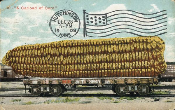 Photomontage of flatbed train car holding a giant corn cob. Additional train cars and tracks visible in the background. Red text in the upper left corner reads, "10 - 'A Carload of Corn.'" The MK&T painted on the side of the car stands for "Missouri Kansas & Texas Railroad."