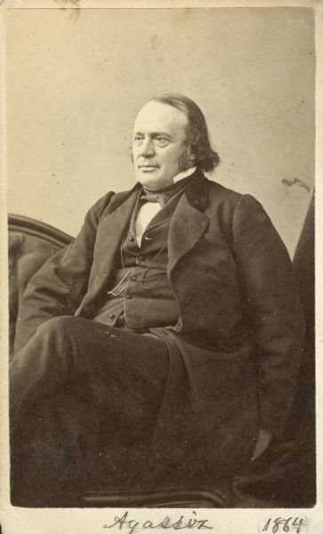 Carte-de-visite portrait of Jean Louis Rodolphe Agassiz (1807-1873), Swiss-born American zoologist, geologist and glaciologist. Founded the Museum of Comparative Zoology in 1860. Founding member of the National Academy of Sciences in 1863. Agassiz is shown sitting in three-quarter profile. Handwritten inscription at bottom reads: "Agassiz 1864."