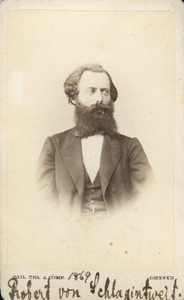 Carte-de-visite portrait of Robert von Schlagintweit (1833-1885), German orientalist, geographer and explorer. Along with his oldest brother Hermann, Robert was one of the first Europeans to cross the Kunlun Mountain range. He became a professor of geography at the University of Giessen in 1863. Shown here sitting in three-quarter profile, with a large beard. His name, along with "1869," have been handwritten at the bottom of the image.