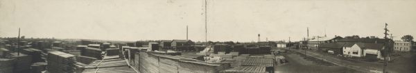 Panoramic view of a lumber yard. Sign in lower left corner reads, "Look Out for the Cars."